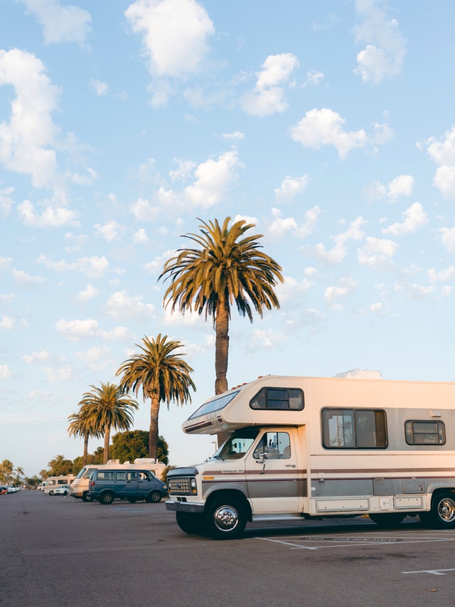 a RV parked in front of a palm tree